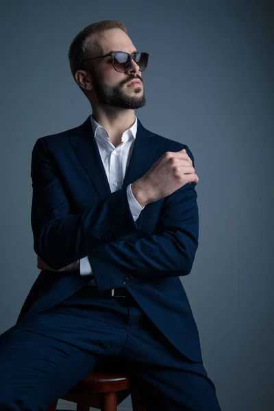 Sentado elegante hombre usando gafas de sol está soñando lejos — Foto de Stock