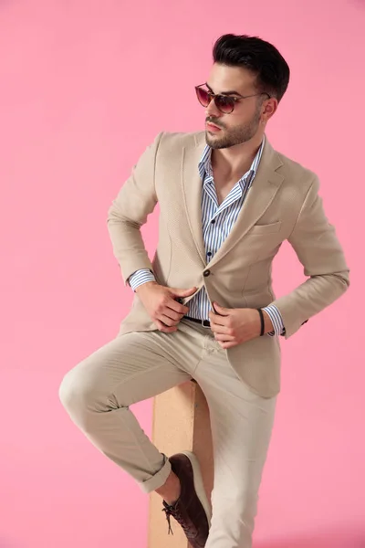 Smart casual man fixing coat seated on a wooden box — Stock Photo, Image