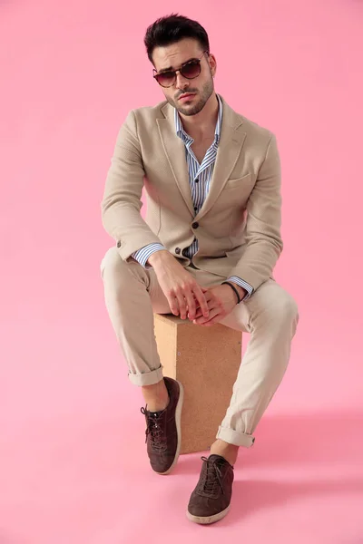 Smart casual man wearing a suit seated on a wooden box — Stock Photo, Image