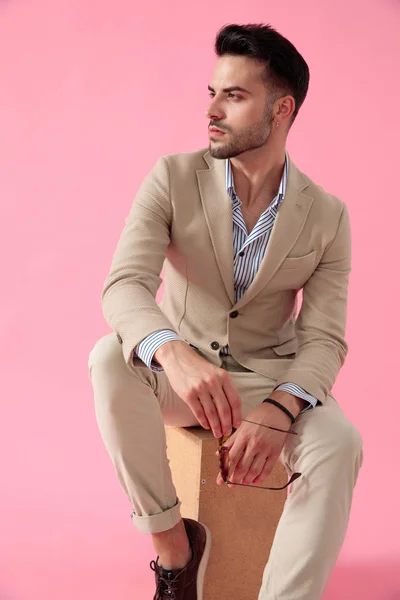 Aantrekkelijke jonge man zittend op houten kist — Stockfoto