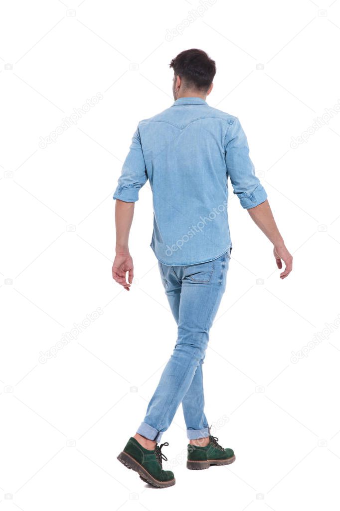 back view of an attractive man wearing denim and walking