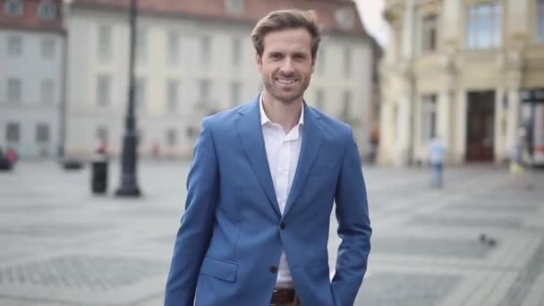 Smiling smart casual holding briefcase moves around in front of the camera, outdoor in the city — Stock Video