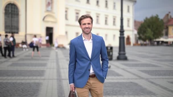 Happy relaxed smart casual man walking with briefcase and hand in pocket in the downtown — Stock Video