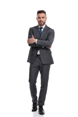 Takım elbise ve kravat giyen genç adam elleri çapraz duruyor