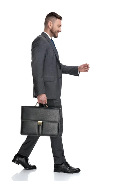 Visão lateral de feliz jovem empresário segurando mala e caminha — Fotografia de Stock