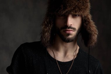 gri arka planda kürk şapka giyen yakışıklı genç adam