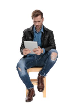 korkmuş bir tablet tutan oturmuş adam