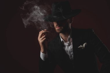siyah arka plan üzerinde smokin sigara çekici dramatik adam