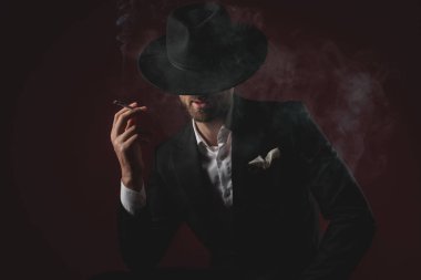 siyah arka plan üzerinde smokin sigara çekici genç adam