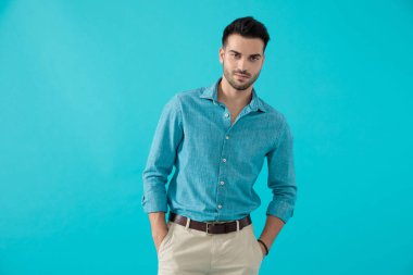 ceplerinde elleri ile duran mavi gömlekli adam