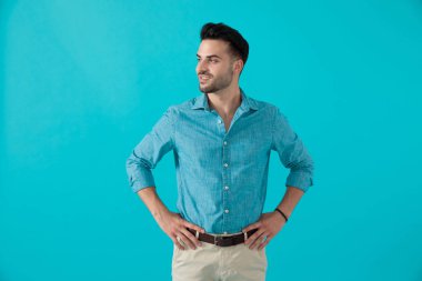 mavi gömlekli adam ayakta ve bir tarafa bakıyor