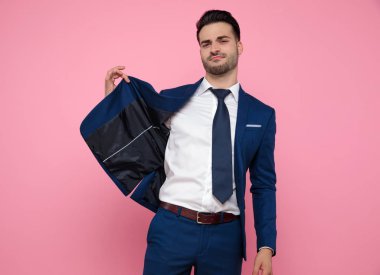 pembe arka plan üzerinde ceket tutan akıllı rahat adam