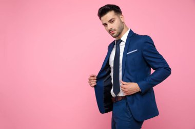 pembe arka plan üzerinde ceket tutan çekici genç adam