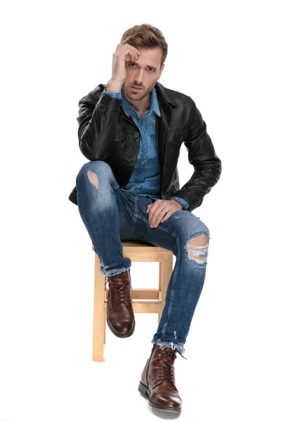 Mann sitzt mit einer Hand auf der Stirn — Stockfoto