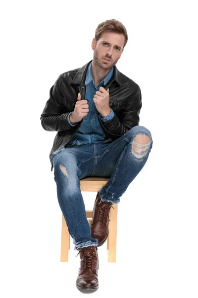 Sitzender Mann fixiert den Kragen seiner Jacke — Stockfoto