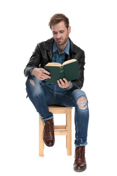 Сидящий человек читает книгу неудовлетворенным — стоковое фото