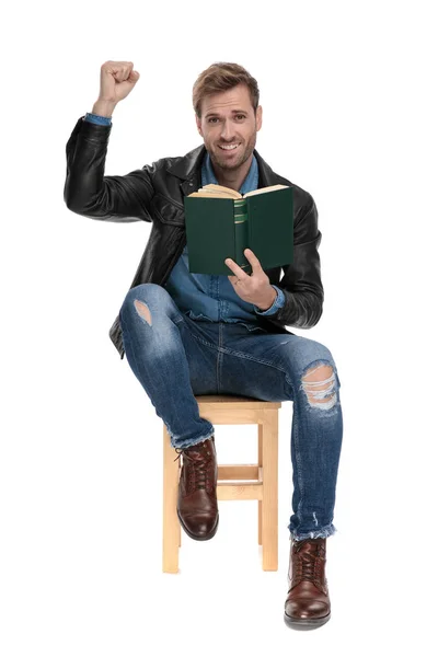 Mann sitzt mit Buch und erhobener Hand — Stockfoto