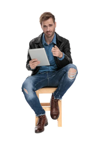Siedzący mężczyzna z tabletem skierowanym do przodu — Zdjęcie stockowe