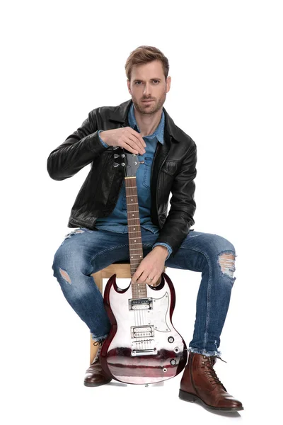 Siedzący mężczyzna trzyma gitarę — Zdjęcie stockowe
