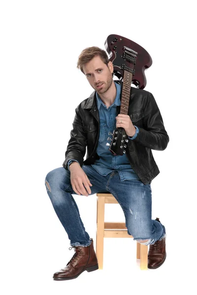 Sitzender Mann mit seiner Gitarre auf dem Rücken — Stockfoto