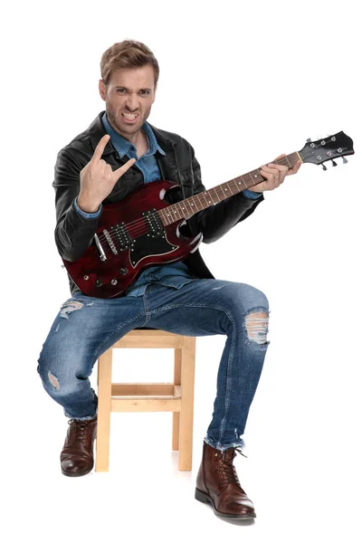 Sitzender Mann spielt aggressiv auf seiner Gitarre — Stockfoto