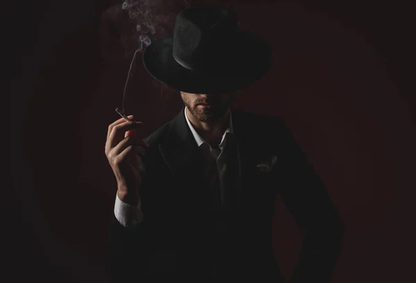 Mysterious young man smoking on black background — Stock Photo, Image