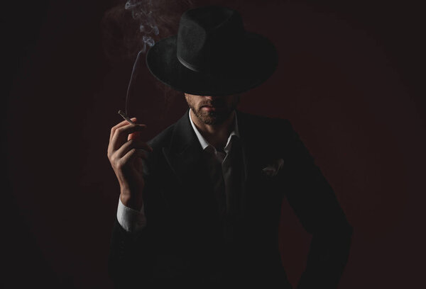 mysterious young man smoking on black background