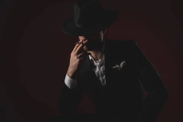 Mysterious dramatic man smoking cigarette on black background — Stock Photo, Image