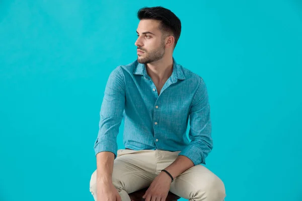 Hombre de camisa azul sentado y mirando a un lado — Foto de Stock