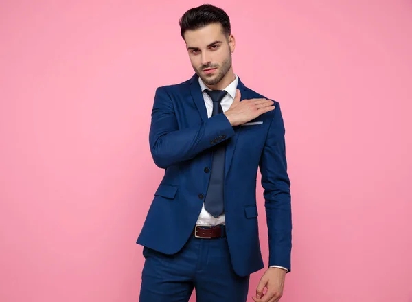 Красивый молодой человек в темно-синем костюме на розовом фоне — стоковое фото