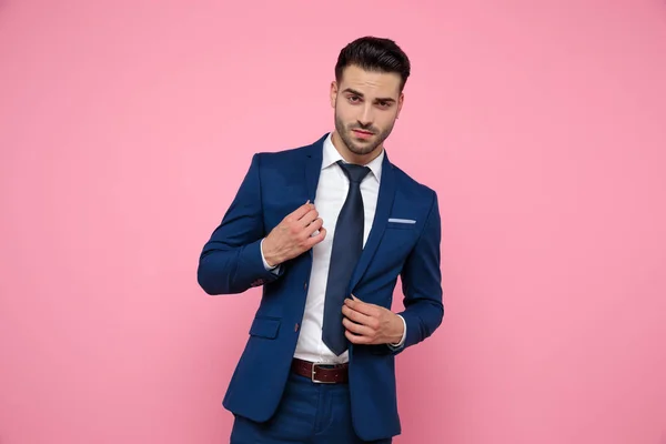 Confident young man holding coat on pink background — Stock Photo, Image