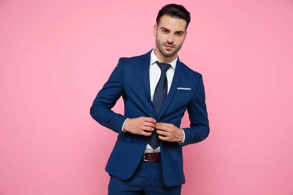 Handsome young man fixing coat on pink background — Stock Photo, Image