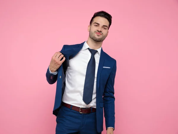 Joven guapo sosteniendo abrigo sobre fondo rosa —  Fotos de Stock