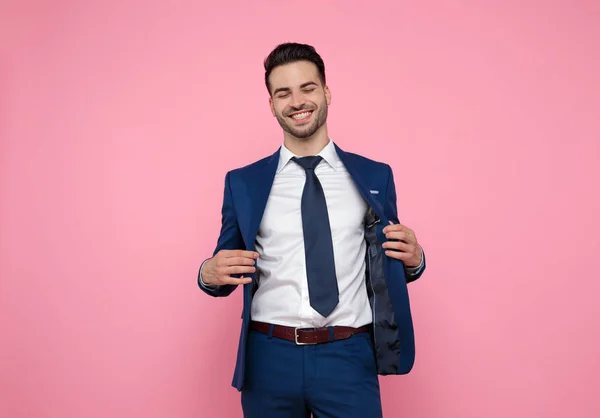 Attractive young man smiling and holding coat on pink background — Stock Photo, Image