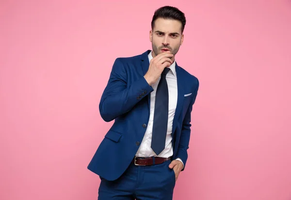 Красивый молодой человек в темно-синем костюме на розовом фоне — стоковое фото