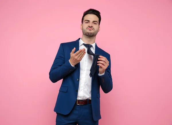 Smart casual man holding tie on pink background — Stock Photo, Image