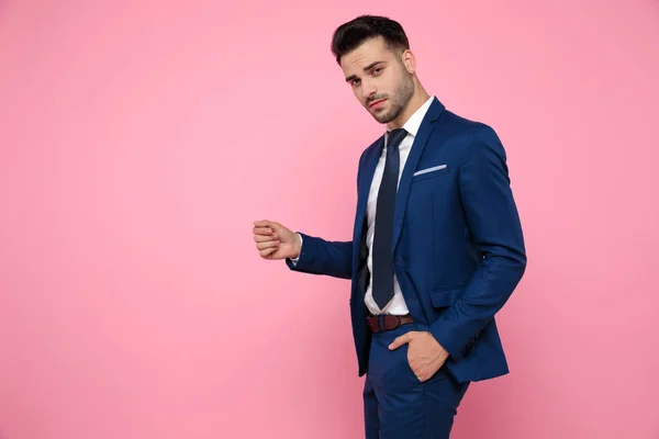 attractive young man wearing navy blue suit on pink background