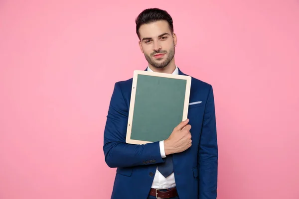 Smart Casual man houdt een leeg bord op roze achtergrond — Stockfoto
