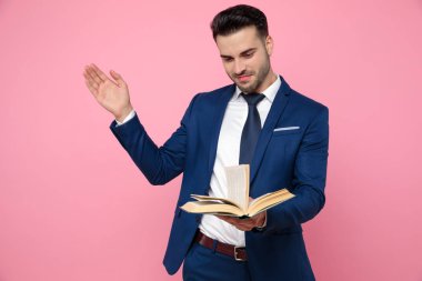 pembe arka plan üzerinde bir kitap tutan akıllı rahat adam