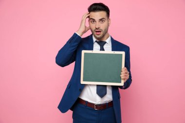 pembe arka plan üzerinde boş bir tahta tutan karışık genç adam