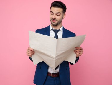 yakışıklı genç adam pembe arka plan üzerinde gazete okuma