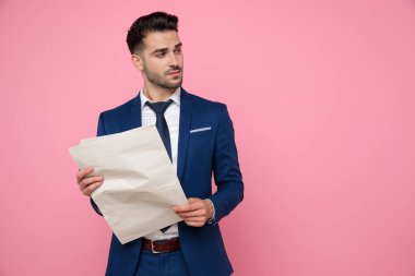 pembe arka plan üzerinde gazete tutan çekici genç adam