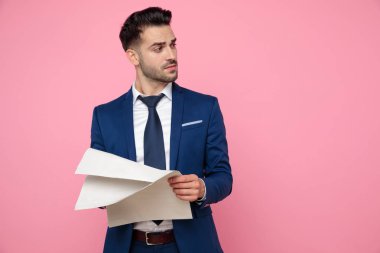 pembe arka plan üzerinde gazete tutan çekici genç adam