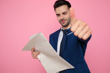 pembe arka plan üzerinde işaret kadar başparmak yapma çekici genç adam