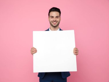 pembe arka plan üzerinde boş tahta tutan çekici genç adam