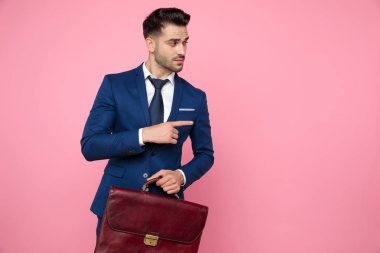 yakışıklı genç adam tutan bavul ve işaret parmak