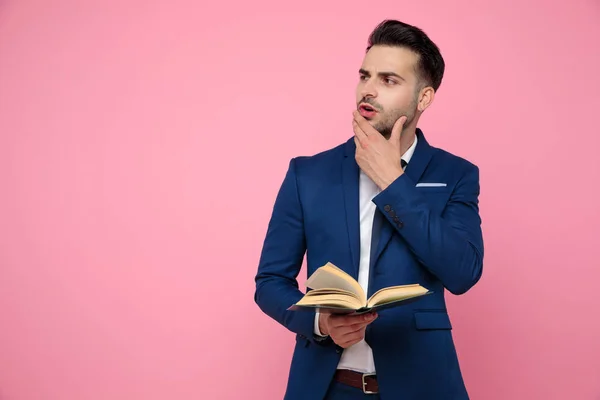 Attrayant jeune homme regardant de côté et la lecture d'un livre — Photo