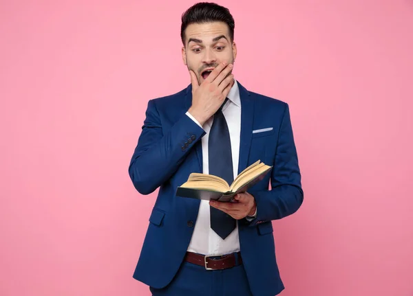 Homem casual inteligente lendo um livro sobre fundo rosa — Fotografia de Stock