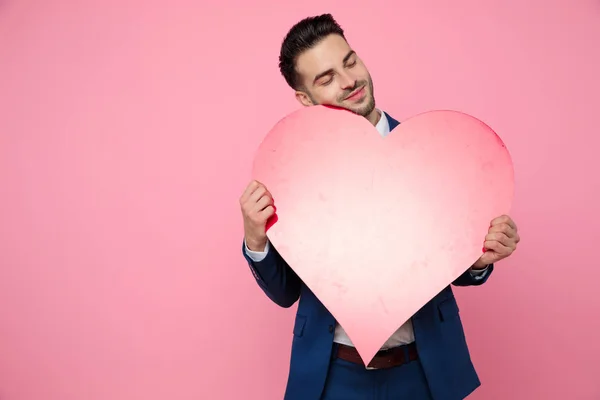 Aantrekkelijke jonge man met een hart op roze achtergrond — Stockfoto