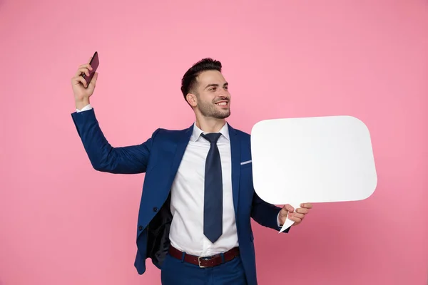 Handsome young man holding speech bubble and cellphone — Stock Photo, Image